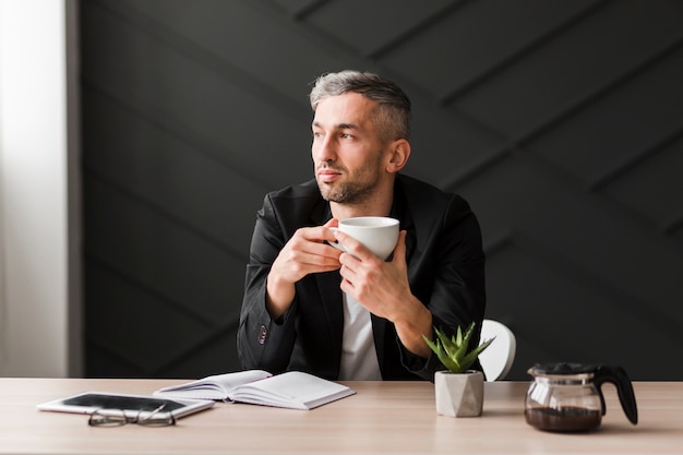 Man with black jacket looking sideways sitting at his desk