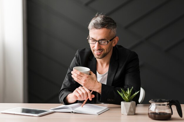 Man with black jacket looking at a white cup