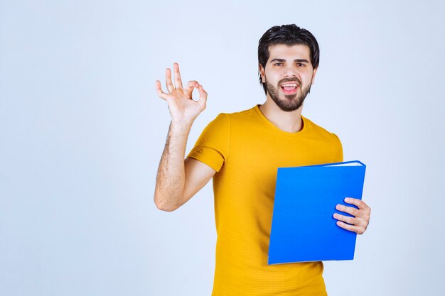 Man with blue folder giving friendly and peaceful poses.