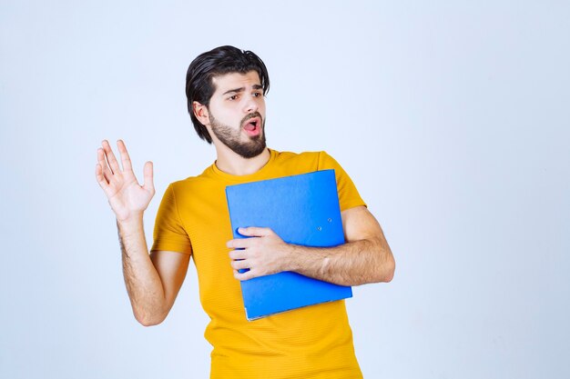 Man with a blue folder looks confused