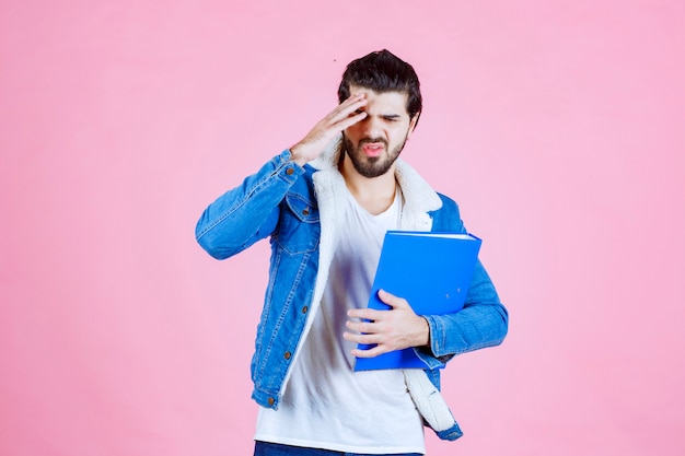 Man with a blue folder looks terrified and tired