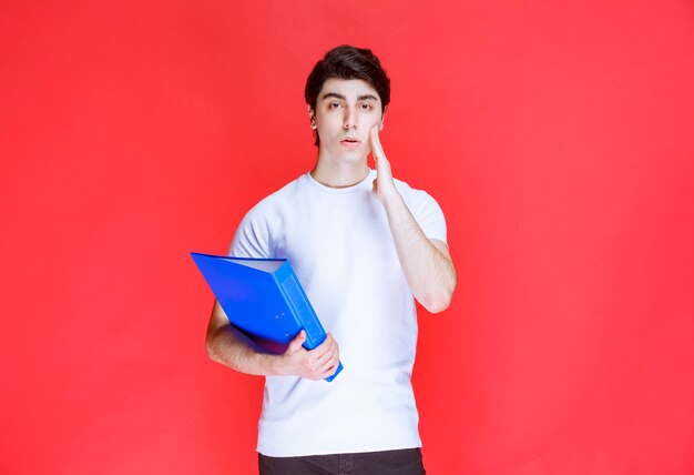 Man with a blue folder looks tired and thoughtful. 