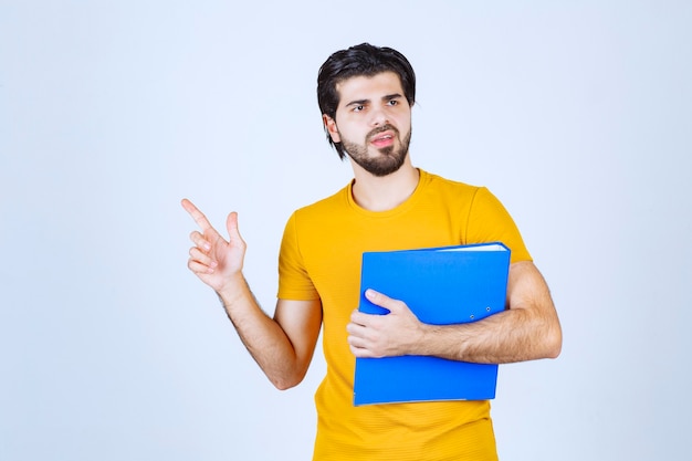 Man with a blue folder pointing his collegue on the left side and talking with emotions.