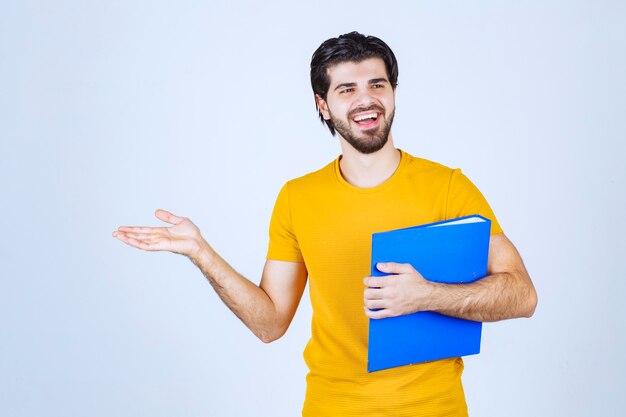 Man with a blue folder pointing his collegue on the left side and talking with emotions.