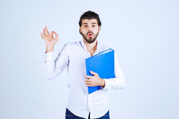 Man with a blue folder showing enjoyment sign