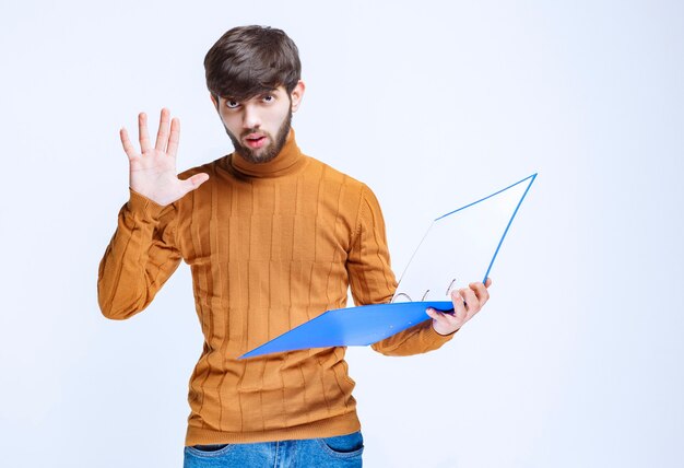 Man with a blue folder stopping something.