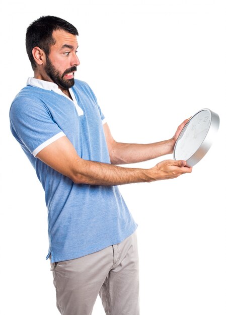 Man with blue shirt holding clock