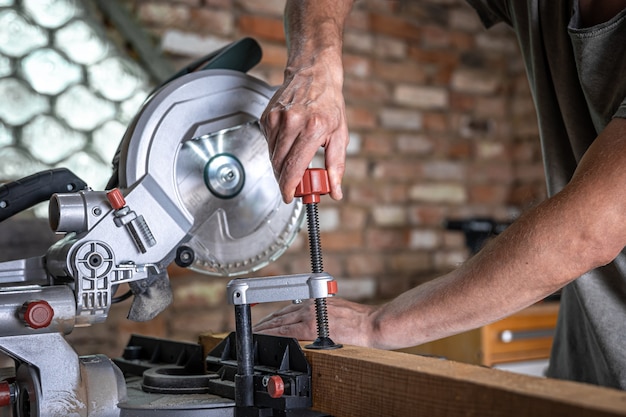 Free photo a man with a board and miter saw close up, concept building and repair.