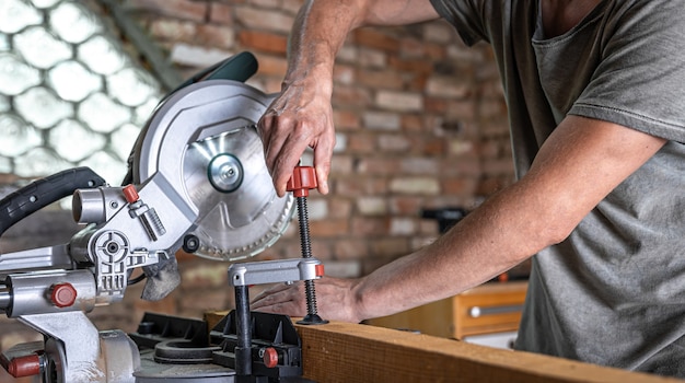 A man with a board and miter saw close up, concept building and repair.