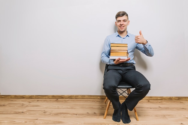 Free photo man with books gesturing thumb-up