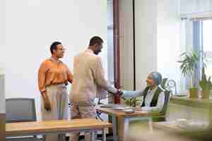 Free photo man with box of belongings being introduced to coworkers at his new job