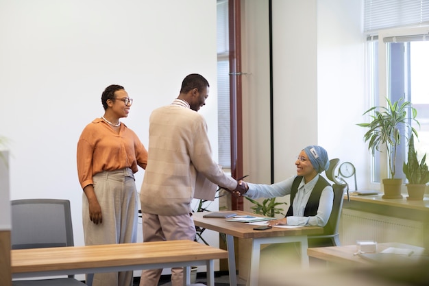 Man with box of belongings being introduced to coworkers at his new job