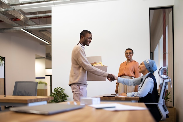 Free photo man with box of belongings being introduced to coworkers at his new job