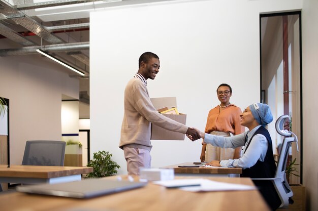 Man with box of belongings being introduced to coworkers at his new job