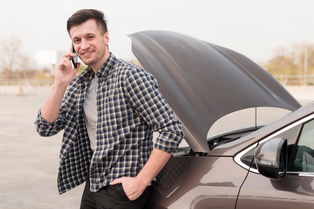 Man with broken car talking over phone