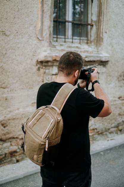 Uomo con una borsa fotografica marrone che cattura foto in una città vecchia