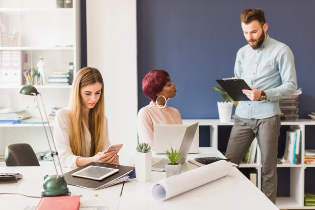 Man with clipboard near female colleagues