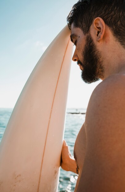 Free photo man with closed eyes holding surfboard