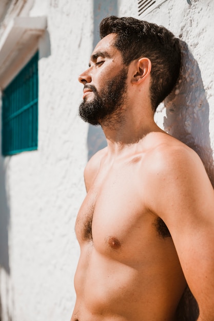 Man with closed eyes relaxing near wall