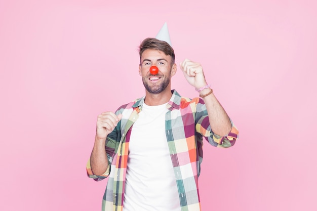Man with clown nose dancing on pink background