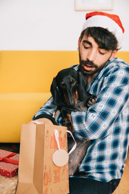 犬とクリスマスの帽子を持つ男