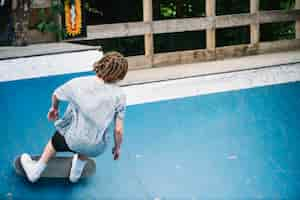 Free photo man with dreadlocks on skateboard