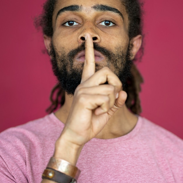 Man with dreads using the silence sign