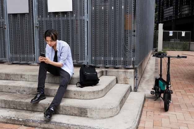 Man with electric bicycle in the city using smartphone