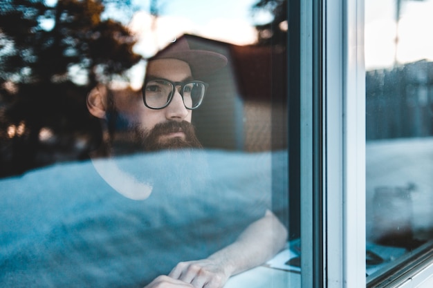 Man with eyeglasses looking through the window