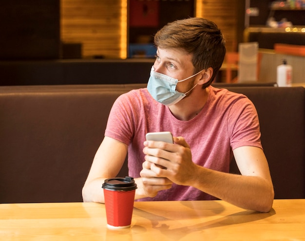 Man with face mask on looking on the window