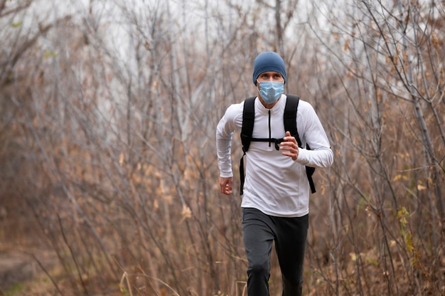 Foto gratuita uomo con la maschera per il viso in esecuzione nel bosco