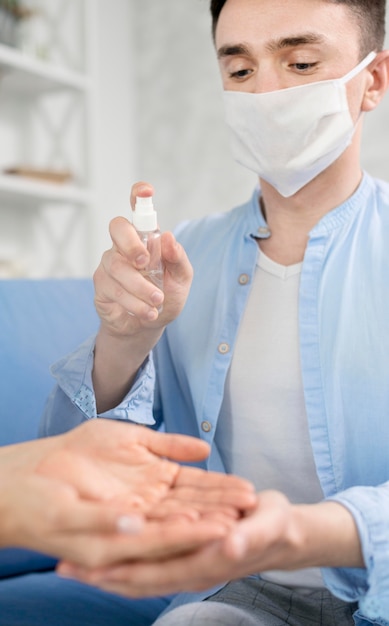 Man with face mask sanitizing hands