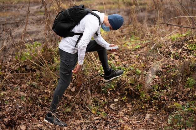 Free photo man with face mask walking through woods