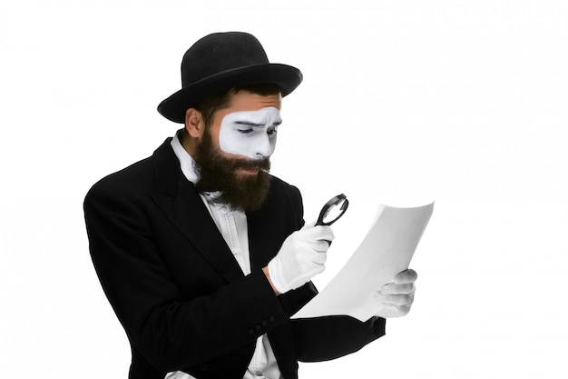 Man with a face mime reading through magnifying glass