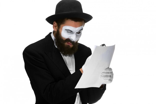 Man with a face mime reading through magnifying glass