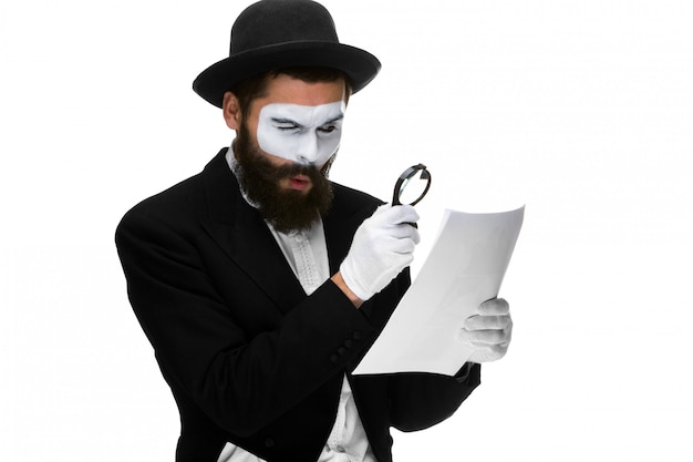 Free photo man with a face mime reading through magnifying glass