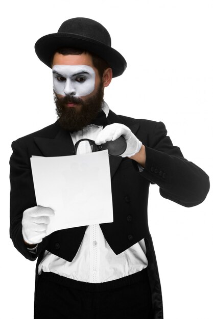 Man with a face mime reading through magnifying glass