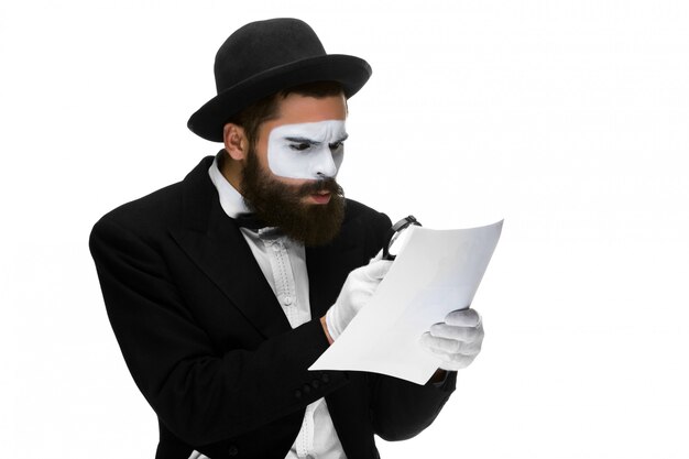 Man with a face mime reading through magnifying glass