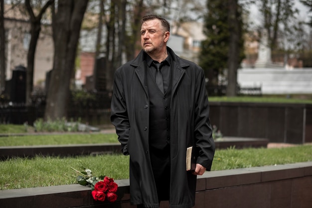 Man with flowers and bible at the cemetery