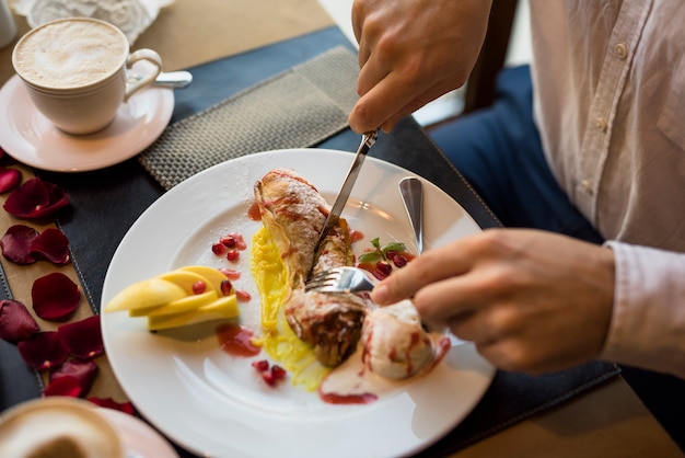 Man with fork and knife cutting delicious fresh dessert in restaurant