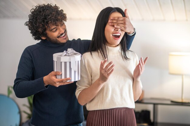 Man with gift covering his eyes to woman