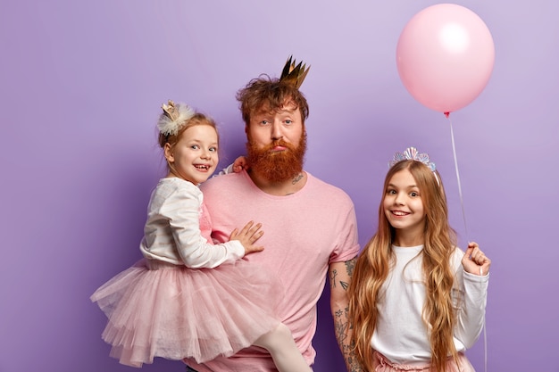 Бесплатное фото Мужчина с рыжей бородой и его дочери с аксессуарами для вечеринок