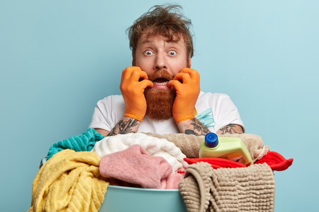 Человек с рыжей бородой стирает белье
