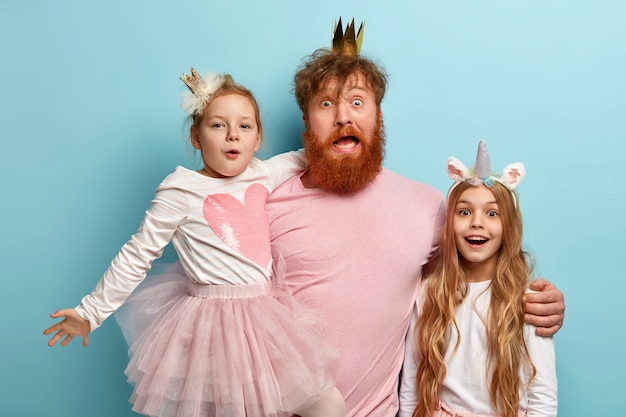 Free photo man with ginger beard and his daughters with party accessories