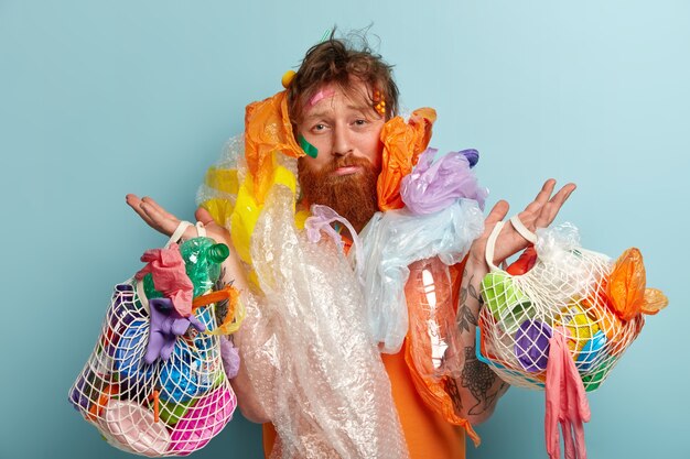 プラスチック廃棄物の袋を保持している生姜ひげを持つ男