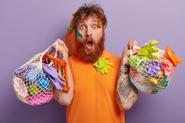 Man with ginger beard holding bags with plastic waste