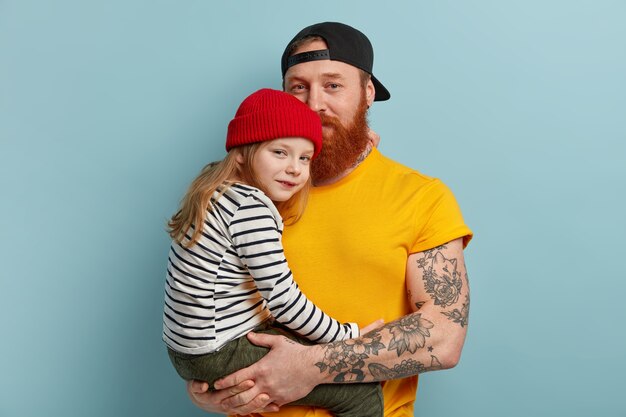 Мужчина с рыжей бородой держит свою дочь
