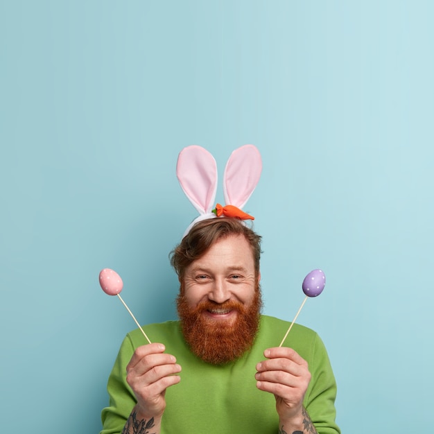 Бесплатное фото Человек с рыжей бородой в яркой одежде и кроличьих ушах