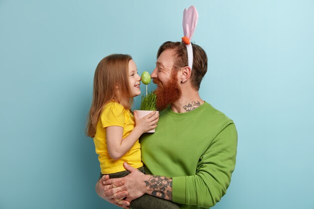 그의 딸을 잡고 화려한 옷과 토끼 귀를 입고 생강 수염을 가진 남자
