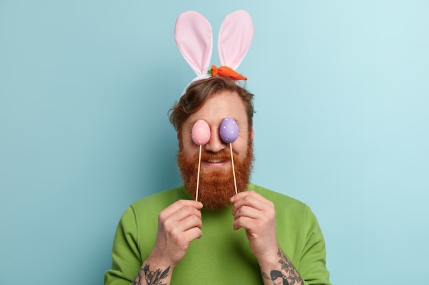 Foto gratuita uomo con barba allo zenzero che indossa abiti colorati e orecchie da coniglio